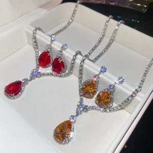 Detailed view of teardrop zircon necklace and earring sets in red and amber gemstones