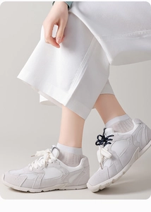Side view of women's white mesh sneakers with suede panels on model's feet