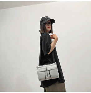 White nylon messenger bag with zipper pockets shown on a person for size and style