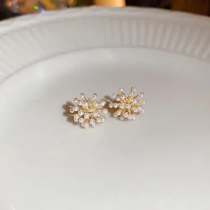Boucles d'oreilles perles dorées en forme de flocon sur un plateau blanc chic