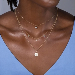 Three-layer gold necklace with heart, opal-style beads, and round coin pendant on neck