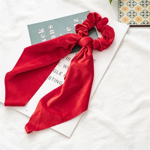 Detail showing red velvet scrunchie with long ribbons on an open magazine backdrop