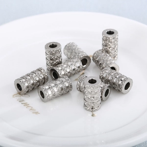 Perles cylindriques en acier inoxydable avec texture moletée sur assiette blanche