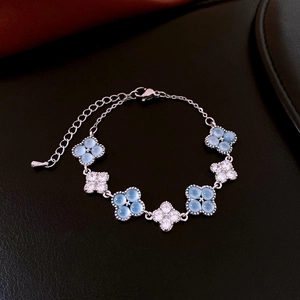 Detail of silver clover bracelet with light blue beads and white crystals on black leather