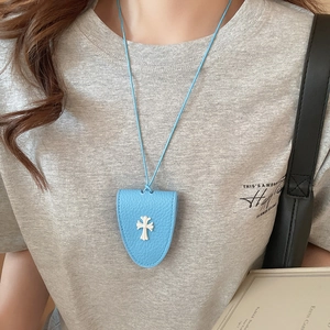 Close-up of sky blue lychee leather glasses clip with a white cross emblem detail