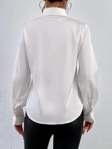 Vista posteriore di una camicia di raso bianco che mostra il drappeggio e il tessuto