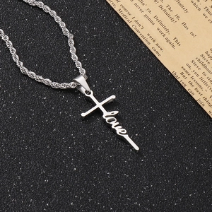 Detailaufnahme des silbernen Kreuzanhängers mit Love-Schriftzug an einer Kordelkette