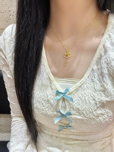 Close-up of golden rocking horse necklace with zircon inlay and tassel on female model neck