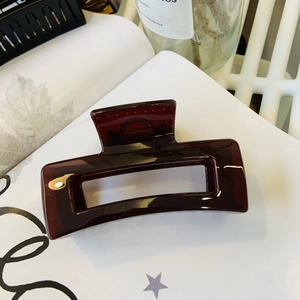Close-up of a large burgundy rectangular hollow hair claw clip on a white background