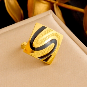 Detailed shot of golden square ring featuring a black S-pattern on textured surface