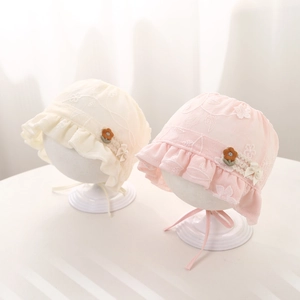 Detail of baby princess hat with delicate floral embroidery and lace ruffles in soft tones