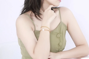 Close-up of double layer gold stainless steel bracelet with white heart charm on model