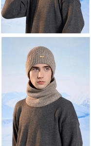 Detail view of khaki ribbed knit beanie and neck warmer set with leather patch on snowy background