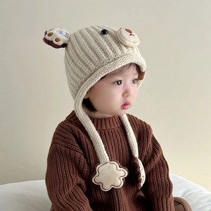 Detailed knit texture of cream bear ear hat with DO Best embroidery and star tassels