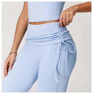 Detail of high waisted flared yoga pants featuring ruched side drawstring and bowknot