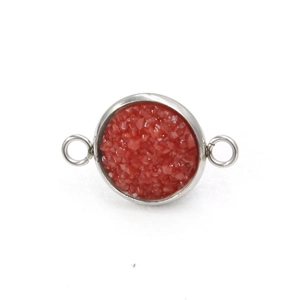 Detail van een zilverkleurige ronde connector met rode hars voor DIY sieraden