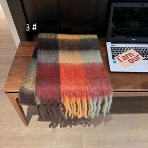 Close-up of thick plaid rainbow scarf with tassels on a wooden table in home setting