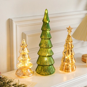 Three lit glass Christmas tree ornaments in green and gold on a white fireplace mantel