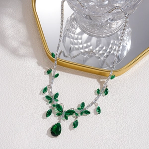 Close-up of silver necklace with green pear-cut gemstones and marquise crystals