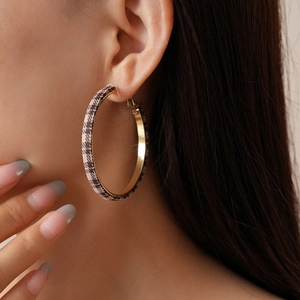 Detail view of large gold hoop earring with black and white houndstooth fabric wrap