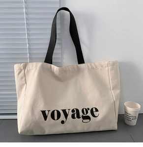 Detail of beige canvas tote bag with voyage lettering on a table near shutters