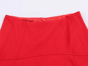Close-up of red skirt waistline detail with textured fabric and zipper closure