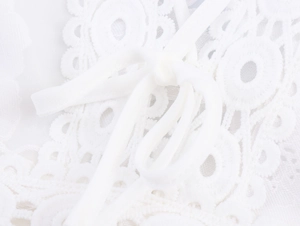 Close-up of elegant white lace dress detail with a delicate ribbon bow accent