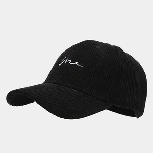 Gros plan détaillé sur la texture du velours côtelé et la broderie 'me' sur la casquette