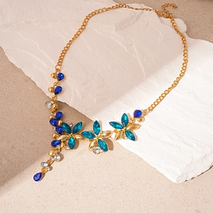 Detail shot of vintage flower necklace with blue crystals and gold chain on stone