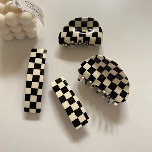 Chic black and white checkerboard hair claw and clip set on a minimalist background
