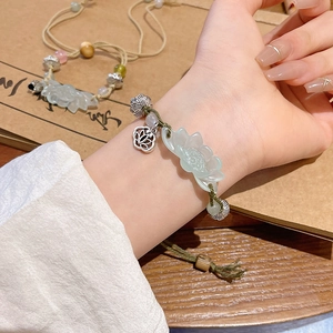 Detailed view of vintage jade bead bracelet with silver charms on female wrist