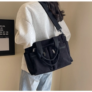 Detailed view of black corduroy shoulder bag with multi-pockets and adjustable strap