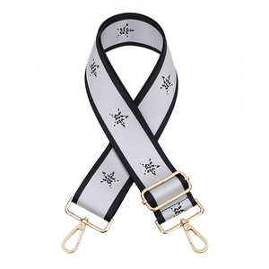 Close-up of adjustable wide strap with black star patterns and gold metal swivel hooks