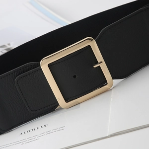 Detail of a wide black elastic waist belt featuring a large square golden metal buckle