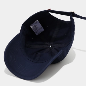 Detail view of navy blue cotton baseball cap interior with wash tag and 100% cotton label