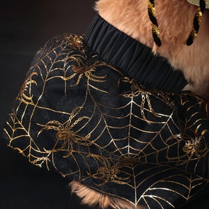 Detail of pet Halloween skirt featuring golden spider web patterns on black mesh fabric