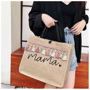 Detail of jute tote bag featuring 'mama' print, colorful tassels, and black handles