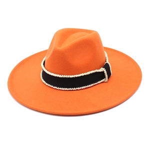 Detail of orange wool fedora with black ribbon band featuring white pearl bead accents