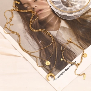 Detailed view of layered 18K gold plated moon and star pendant necklace and bracelet set