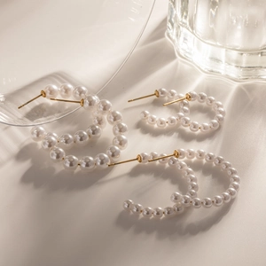 Three pairs of elegant C-shaped white pearl earrings with gold pins in various sizes