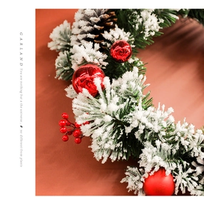 Close-up of frosted Christmas garland with red berries, ornaments, and natural pinecones