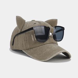 Detail of khaki cat ear baseball cap with decorative aviator sunglasses on the crown