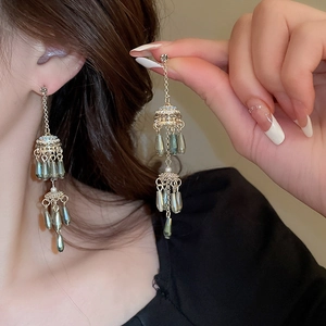 Detail of vintage gold pearl earrings with teardrop tassels and green beads for women