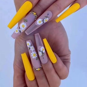Long coffin press-on nails with yellow finish, white daisy patterns, and gold rhinestones