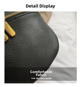 Close-up of black lychee texture leather waist bag with golden metal zipper details