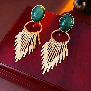 Vintage green stone earrings with golden metal tassels on a luxury wooden box