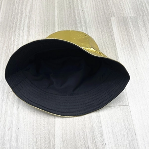 Detail of shiny gold metallic bucket hat with smooth texture and black interior lining
