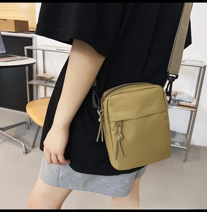 Detail of khaki nylon crossbody bag with adjustable strap and zipper compartment for daily use