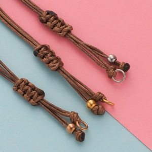 Vue détaillée de bracelets en cordon de cire marron faits main avec perles en métal dorées