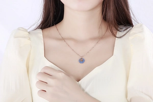 Detailed shot of rose gold zodiac coin pendant with blue enamel on a model's neck